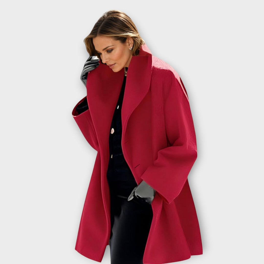 Femme de profil en manteau rouge cerise à large col, gants gris et ensemble noir en dessous. 2