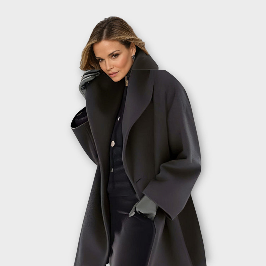 Femme en manteau noir à large col châle, gants gris, regard vers l'objectif, tenue sombre assortie. 3