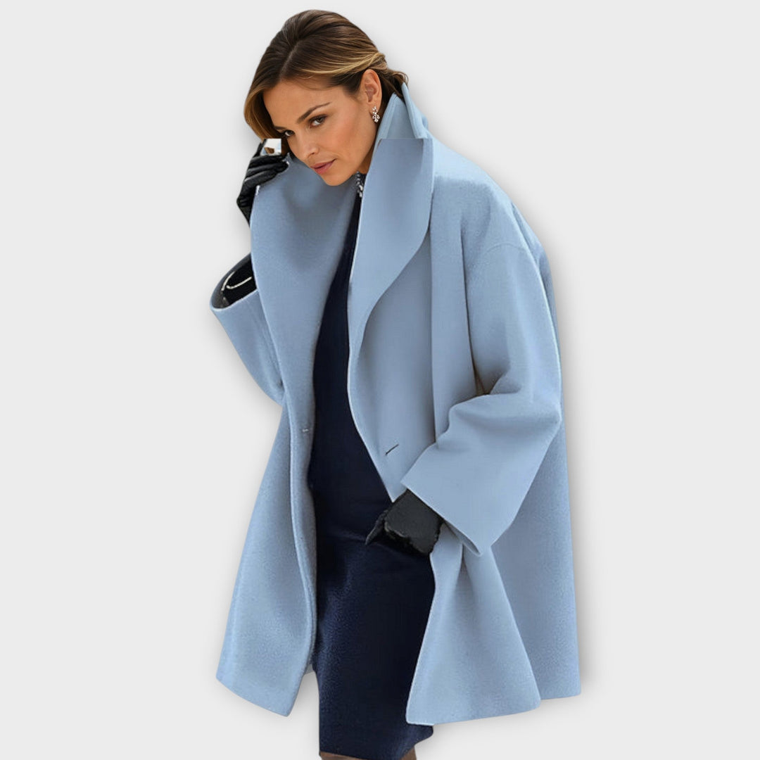 Femme portant le manteau ample bleu ciel à grand col châle, gants noirs, tenue sombre en dessous. 1
