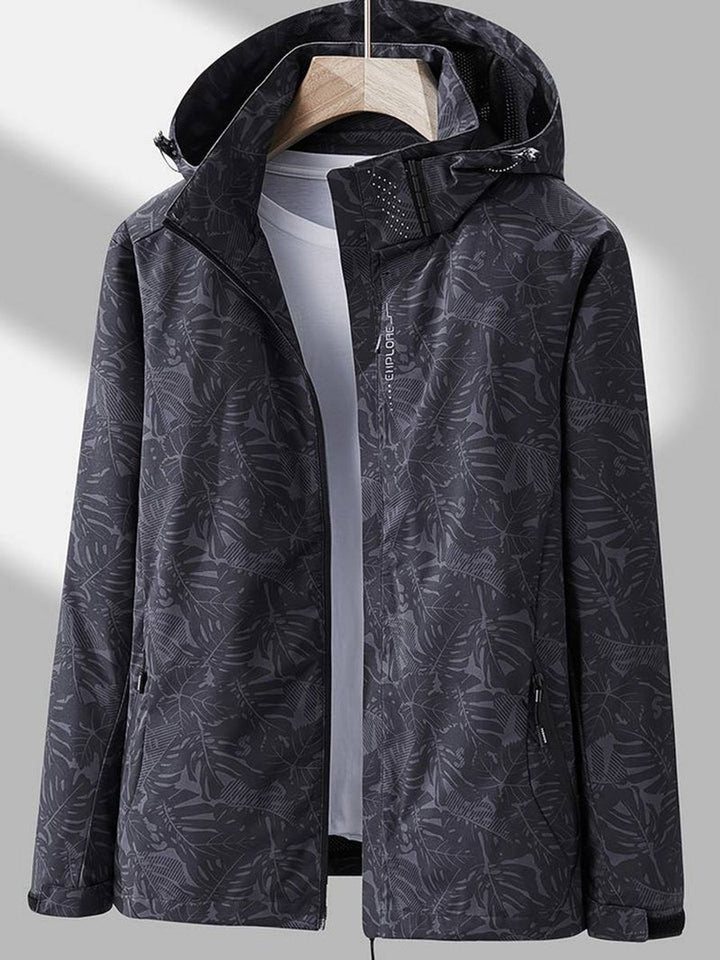 Veste gris anthracite foncé à motif de feuilles, capuche relevée, zip ouvert sur un t-shirt gris clair, vue de face. 6