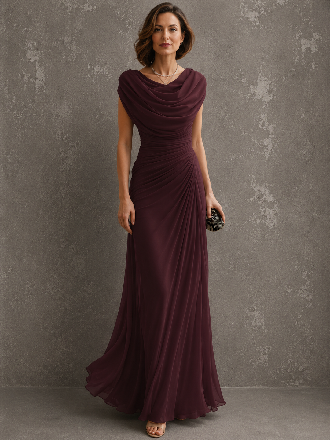 Robe longue bordeaux à col drapé et jupe fluide, portée de face par une femme tenant une pochette. 3