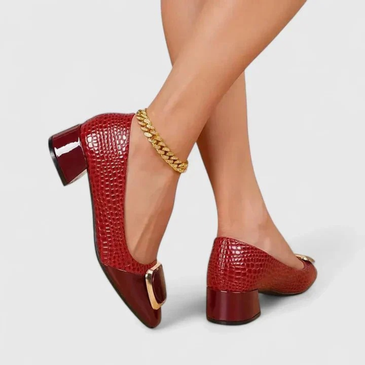 Mocassins rouge bordeaux à effet croco portés, jambes croisées, avec ornement doré et chaîne à la cheville. 5