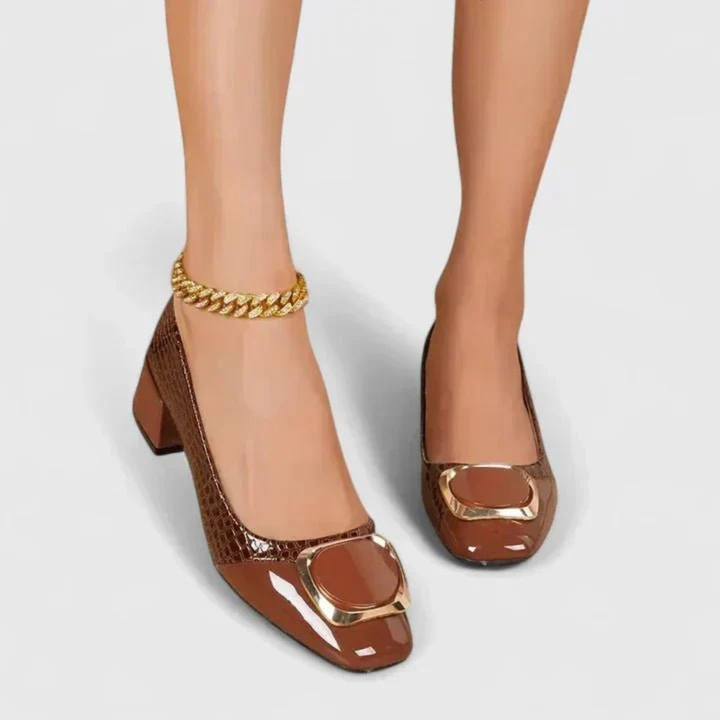Pieds de femme portant les mocassins marron vus de face, avec une chaîne dorée à la cheville. 2