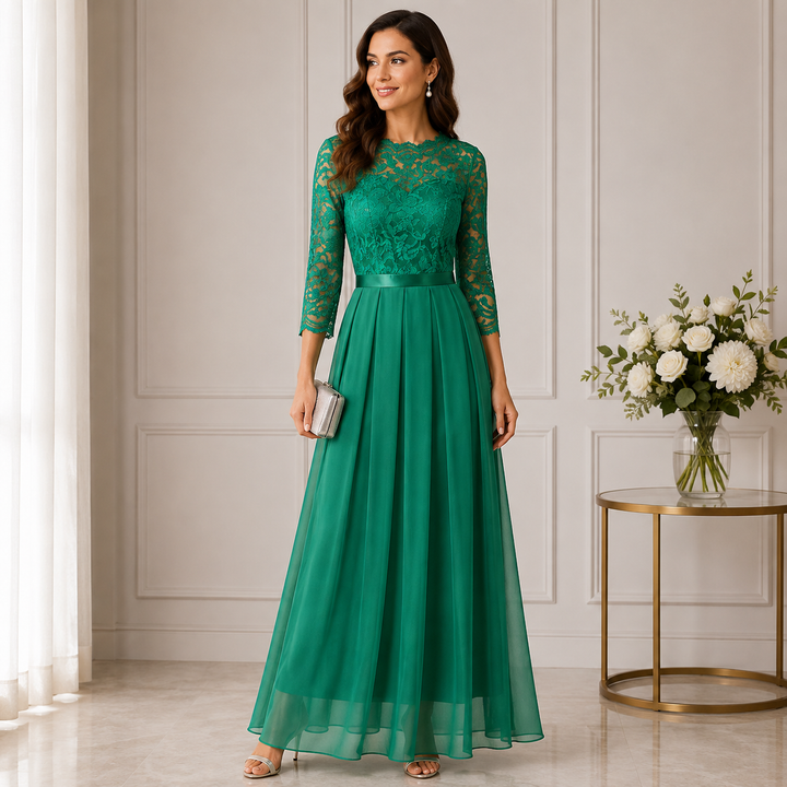 Femme en robe verte à buste en dentelle et jupe plissée en voile, pochette argentée à la main 1