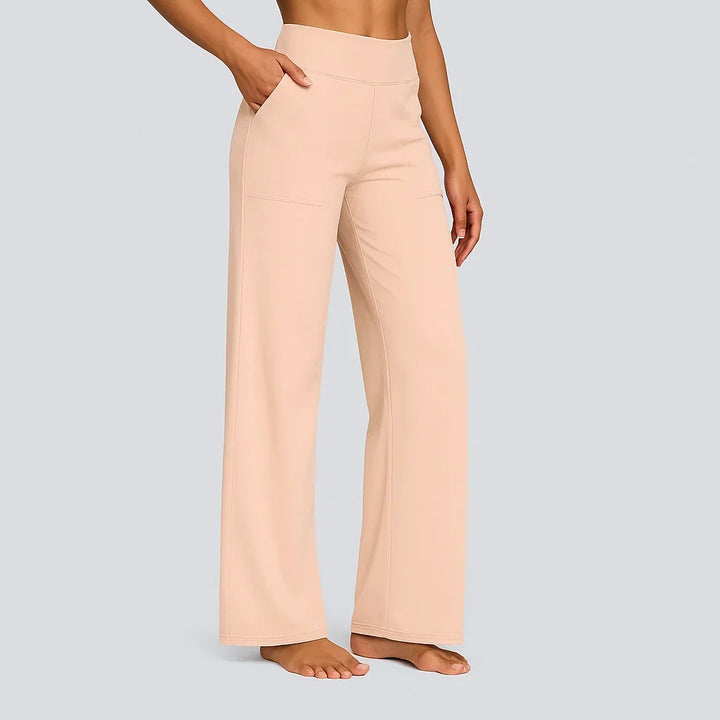 Pantalon rose pêche clair à taille haute, porté par une femme pieds nus, une main dans la poche, vue de côté. 14