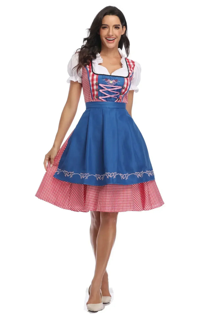 Dirndl à carreaux rouges avec tablier bleu roi brodé et corsage lacé de rose, porté de face par une femme souriante. 7