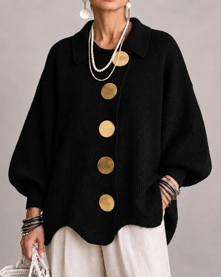 Cardigan noir à manches bouffantes et gros boutons dorés, porté avec un pantalon blanc et des colliers de perles. 8