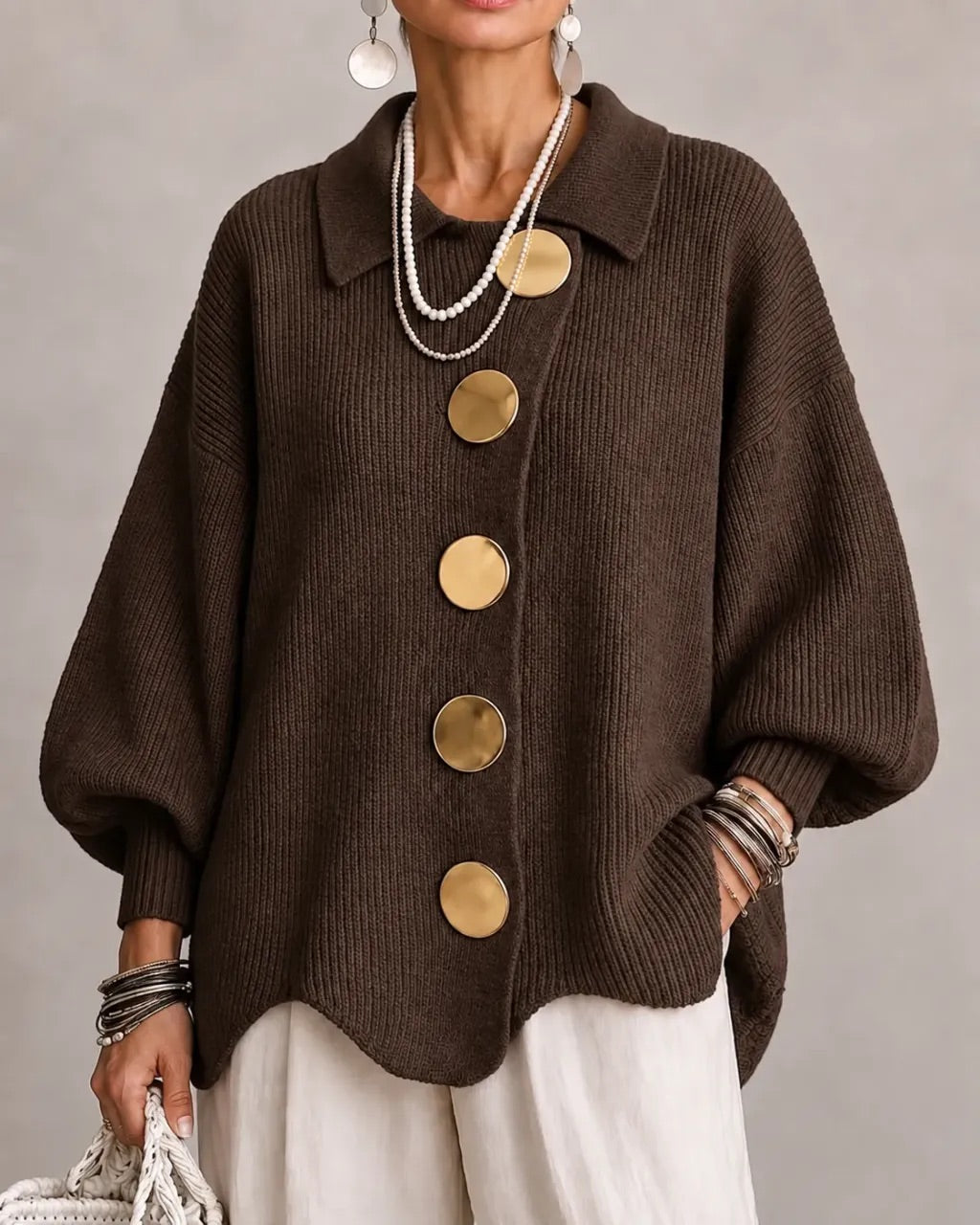 Cardigan marron chocolat à gros boutons dorés et col pointu, porté avec un pantalon blanc. 9