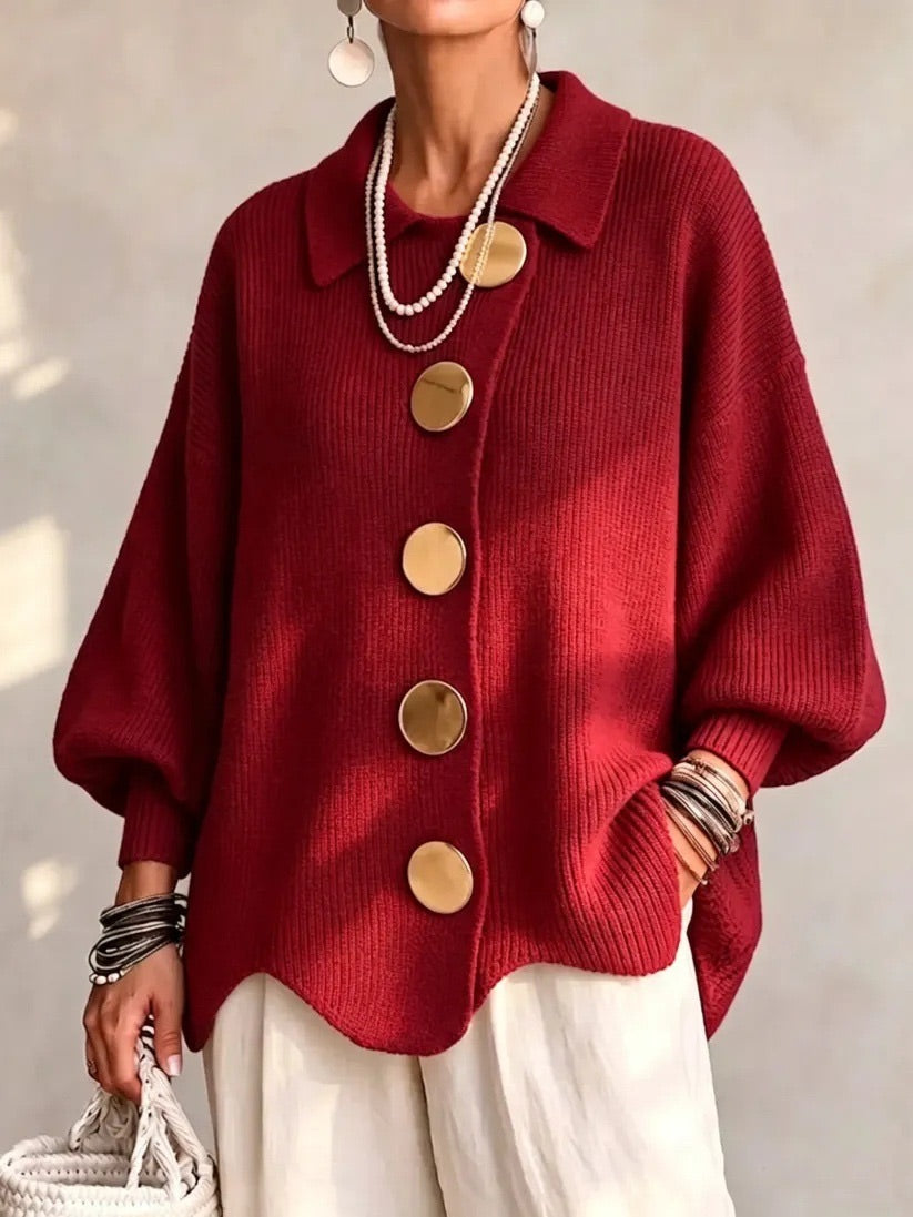 Cardigan rouge vif en maille côtelée à boutons dorés, porté avec un pantalon blanc cassé. 11