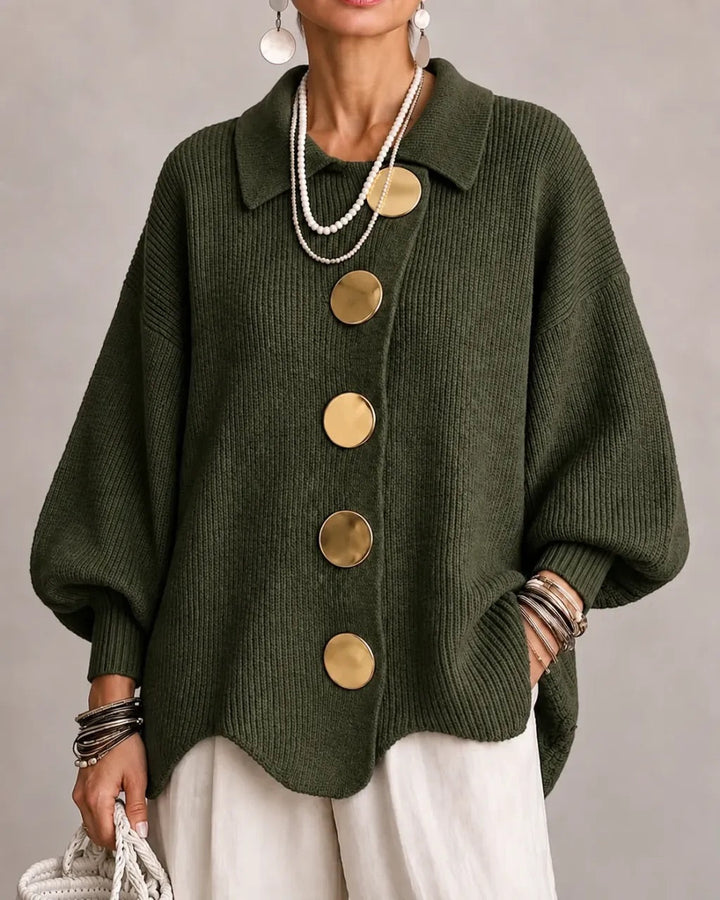 Cardigan vert kaki foncé à gros boutons dorés et manches bouffantes, porté avec un pantalon blanc. 12