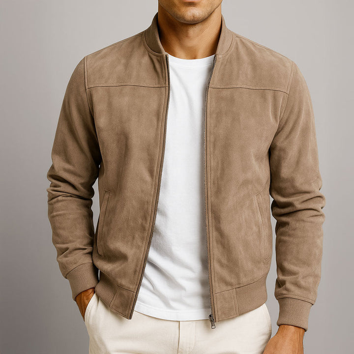 Veste beige taupe zippée portée ouverte sur un t-shirt blanc, une main dans la poche du pantalon clair, vue de face. 1