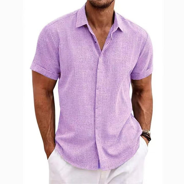 Chemise lilas à manches courtes et col ouvert, portée par un homme avec pantalon blanc, mains dans les poches. 10