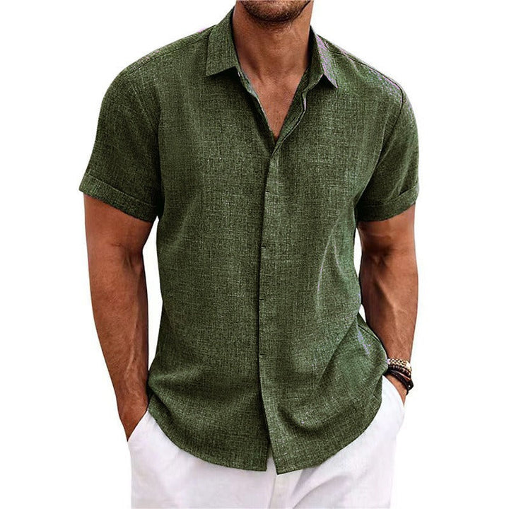 Chemise vert kaki à manches courtes, portée par un homme en pantalon blanc, mains dans les poches, vue de face. 12