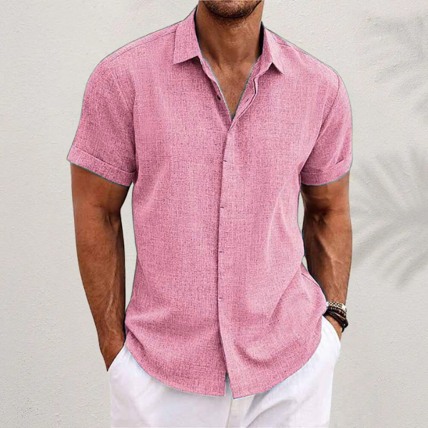 Chemise rose à manches courtes retroussées, portée par un homme en pantalon blanc devant un mur clair. 9