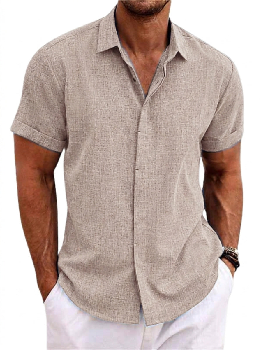 Chemise beige taupe à manches courtes retroussées, portée par un homme avec pantalon blanc, mains dans les poches, vue de face. 1