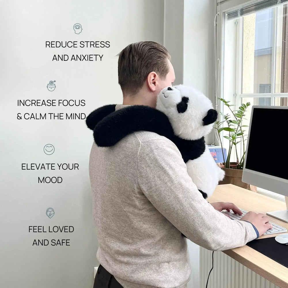 Homme debout devant son ordinateur de bureau, le panda en peluche accroché à son épaule et ses bras noirs autour du cou. 2