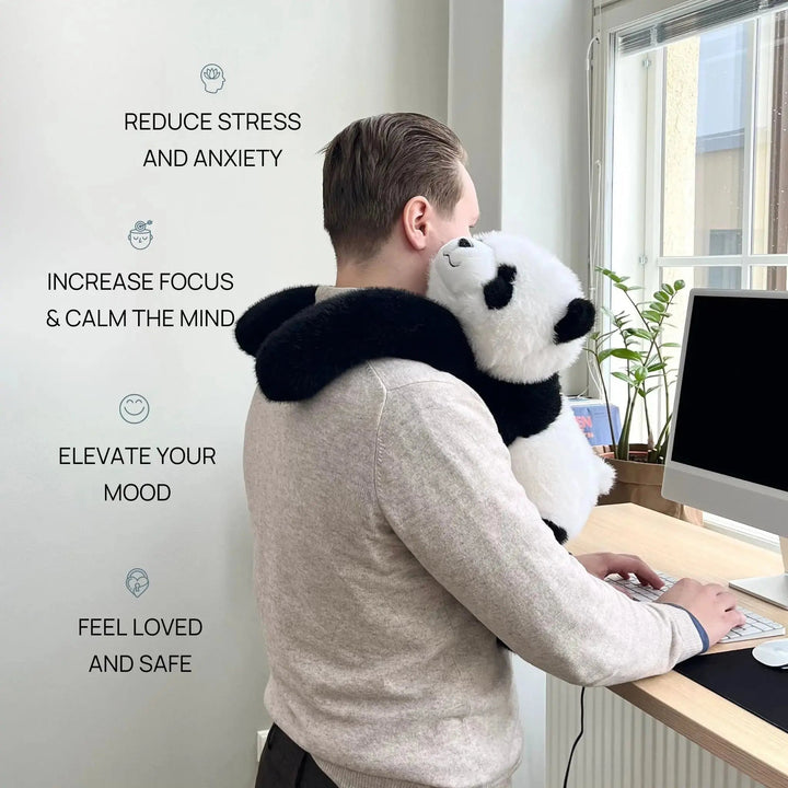 Homme debout devant son ordinateur de bureau, le panda en peluche accroché à son épaule et ses bras noirs autour du cou. 2