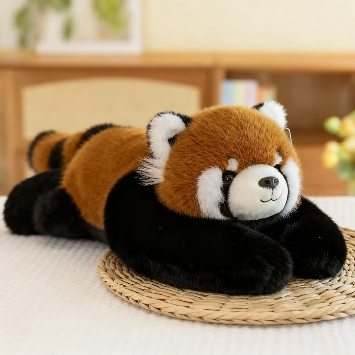 Panda roux en peluche roux, blanc et noir, allongé sur un set de table en paille, ses longs bras noirs devant lui. 13