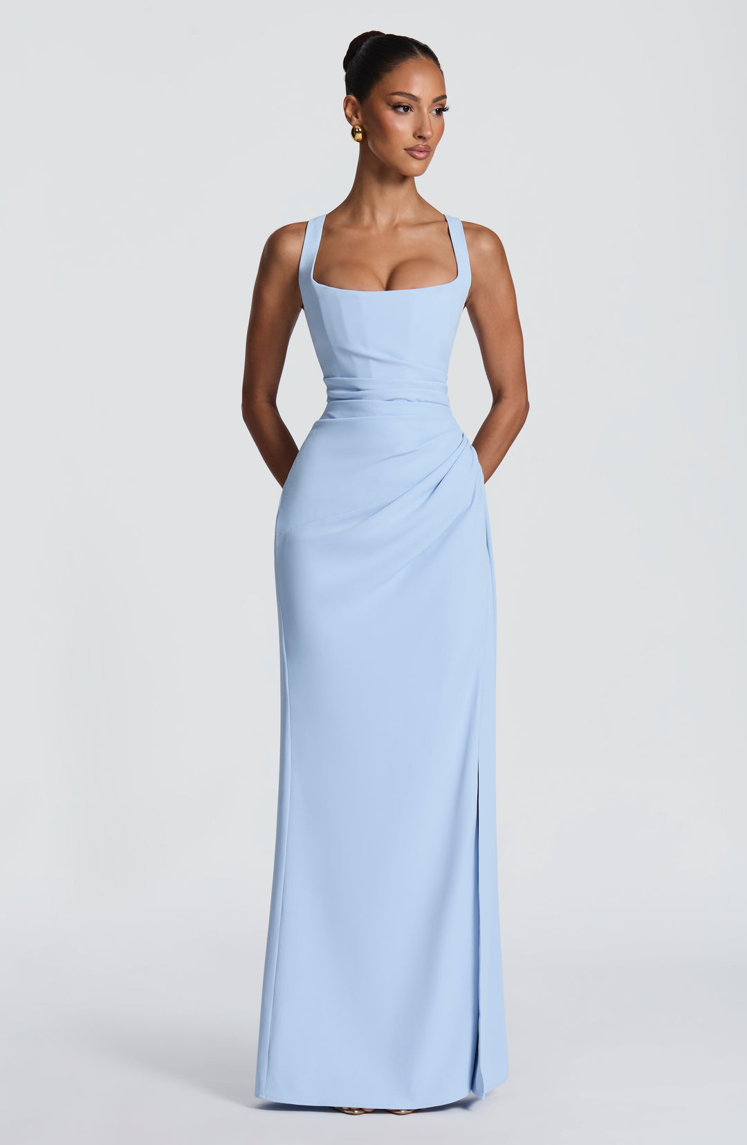 Robe bleu ciel portée de face, fente fermée sur le côté, taille drapée et mains derrière le dos. 27