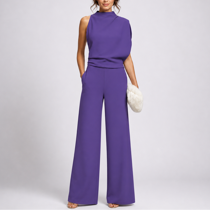 Femme portant la combinaison violette sans manches au drapé asymétrique sur l'épaule, sandales dorées et pochette blanche 3