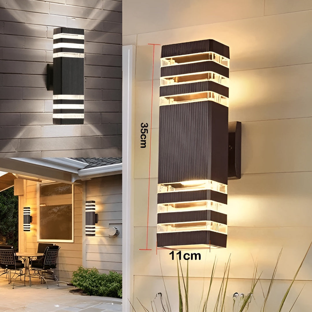 Applique rectangulaire brune à trois bandes transparentes de chaque côté, hauteur 35 cm et largeur 11 cm, allumée contre un mur, avec vues d'ambiance. 6