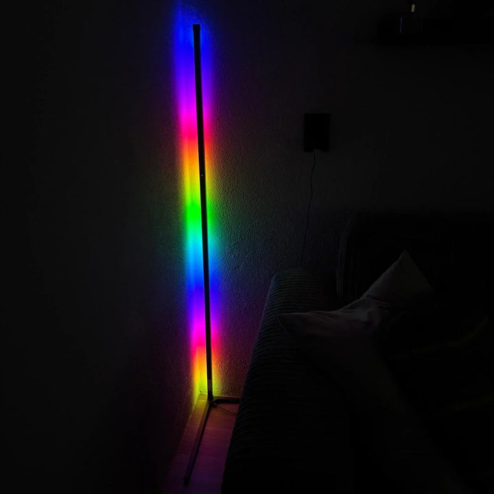 Lampadaire d'angle en mode arc-en-ciel dans une pièce sombre, éclairant le mur de toutes les couleurs à côté d'un canapé. 6