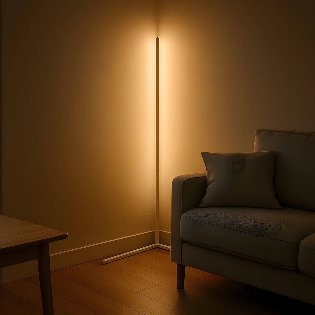 Lampadaire d'angle de couleur claire allumé en lumière chaude, posé près d'un canapé gris et d'une table en bois. 7