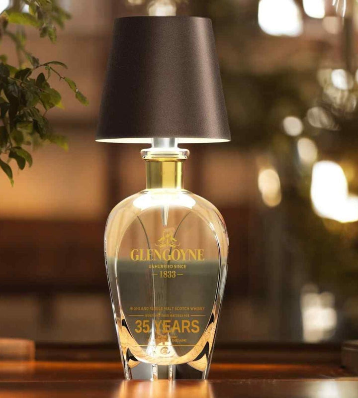 Abat-jour sombre sur une carafe de whisky en cristal, éclairée d'une lumière chaude sur une table en bois. 5