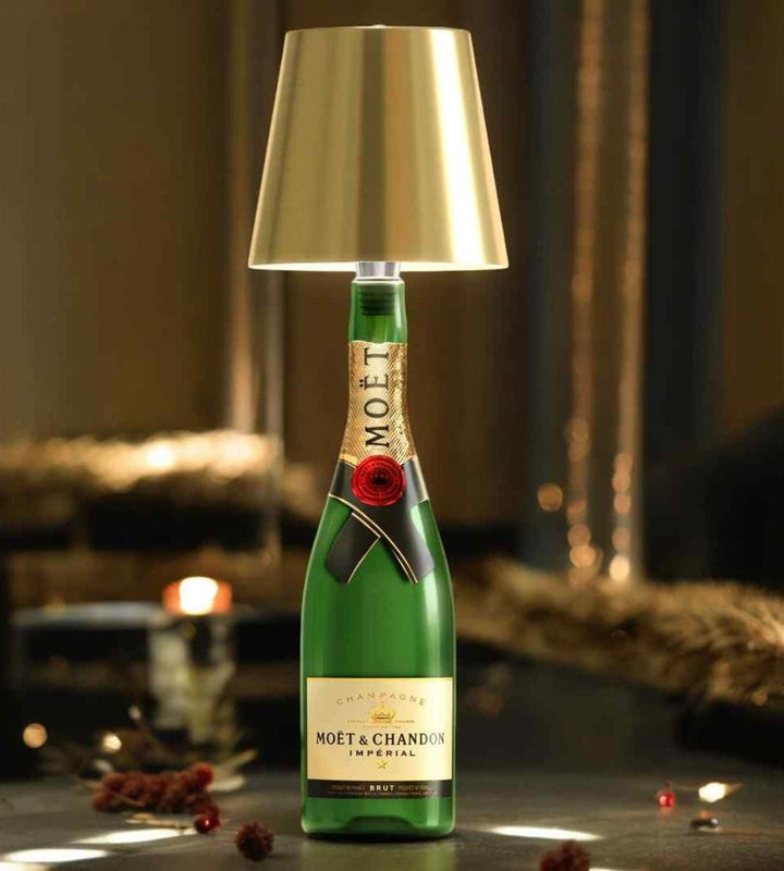 Abat-jour doré posé sur le goulot d'une bouteille de champagne verte, ambiance festive aux lumières chaudes. 1