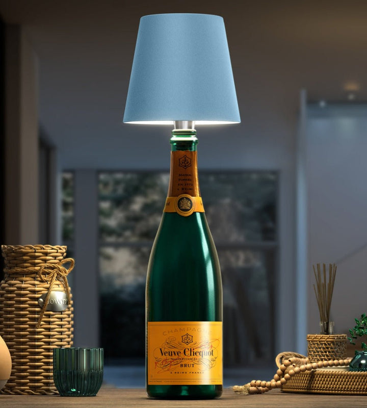 Abat-jour bleu clair posé sur une bouteille de champagne verte, avec paniers tressés et perles en bois. 6