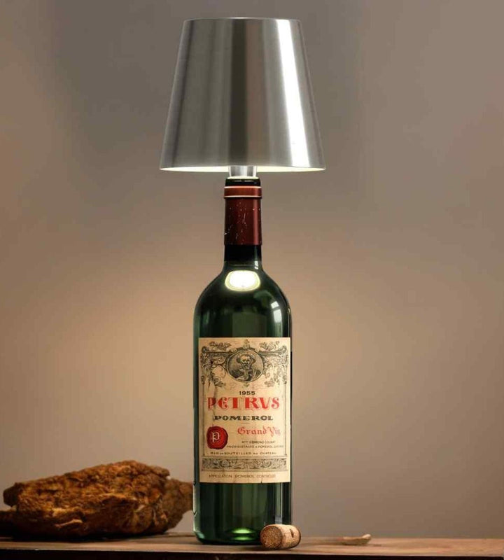 Abat-jour argenté sur une vieille bouteille de vin rouge à étiquette ancienne, avec un bouchon en liège à côté. 7