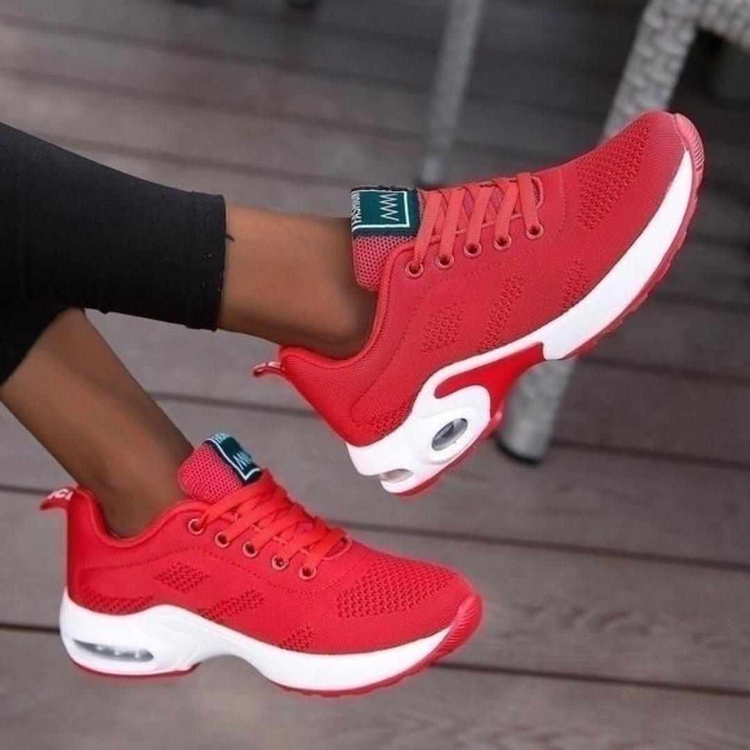 Baskets rouges en maille aérée à semelle blanche avec bulle d'air, jambes croisées et pied levé pour montrer le profil de la chaussure. 7