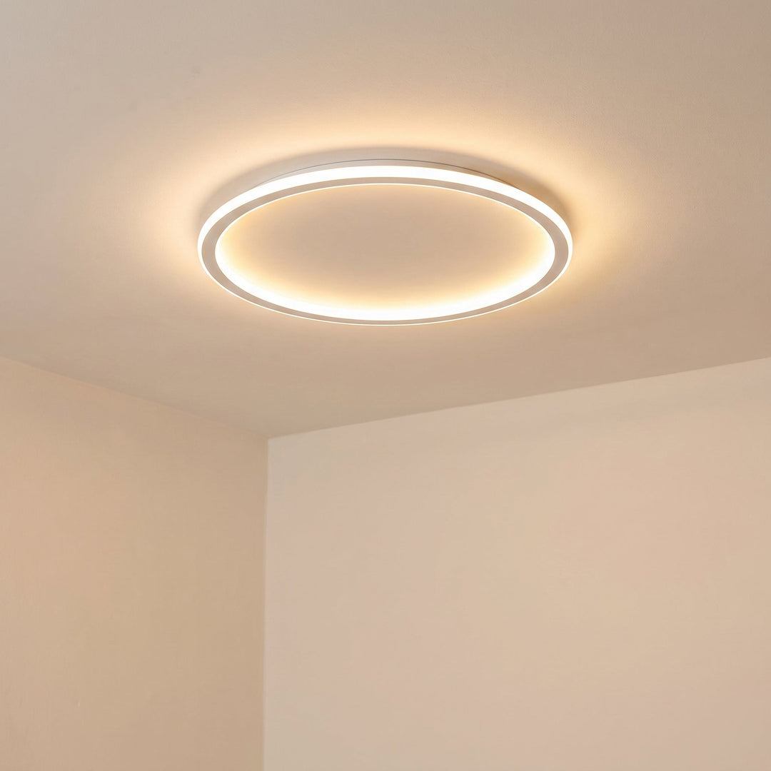 Plafonnier rond blanc allumé, vu en contre-plongée au plafond, avec lumière chaude diffusée sur les murs beiges. 6