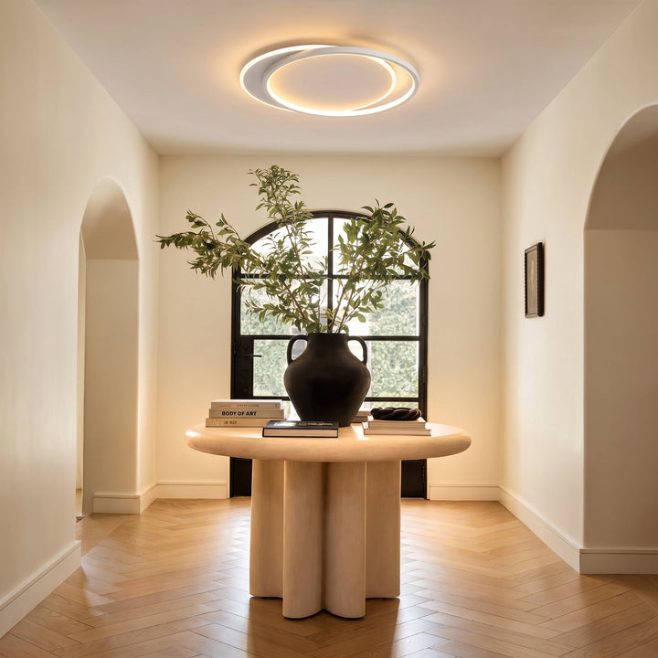Plafonnier allumé au-dessus d'une table ronde en bois claire avec grand vase noir et branchages 6