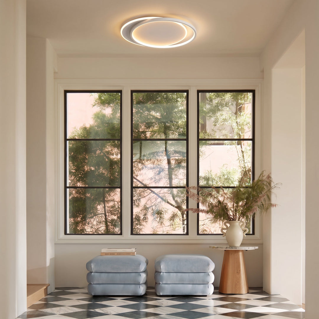 Plafonnier à double anneau dans une pièce lumineuse à trois fenêtres, pouffs bleu-gris et sol en damier 9