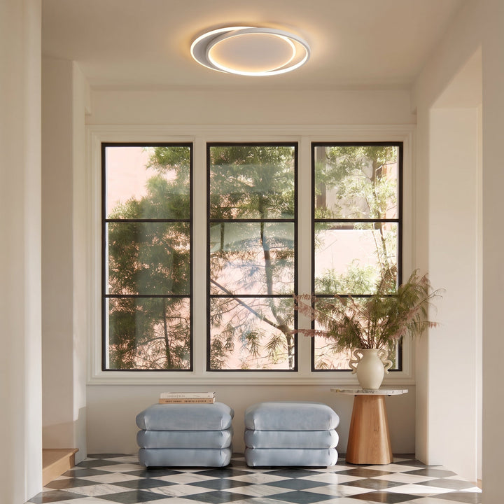 Plafonnier à double anneau dans une pièce lumineuse à trois fenêtres, pouffs bleu-gris et sol en damier 9
