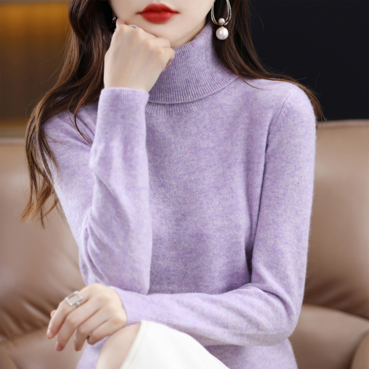 Pull lilas chiné à col roulé porté par une femme, la main sous le menton, assise sur un canapé. 6