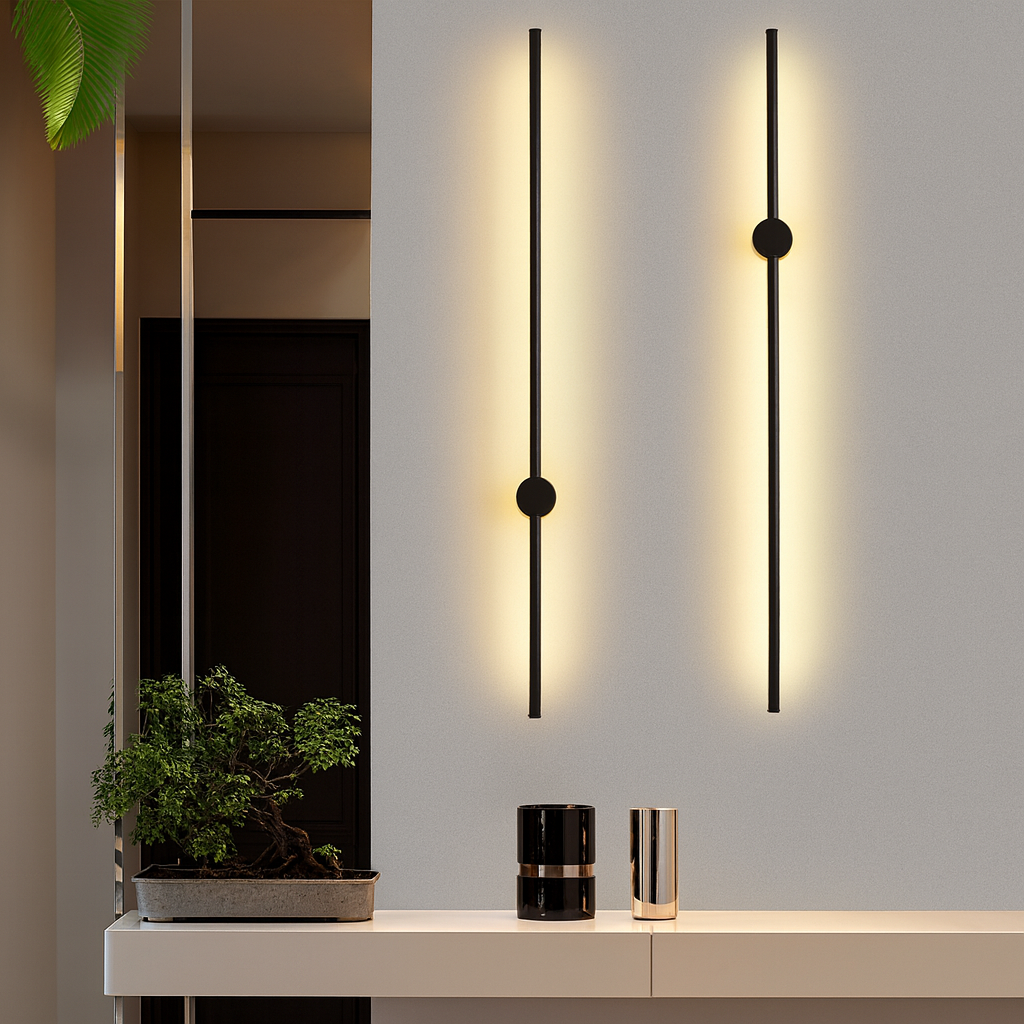 Deux appliques noires verticales allumées sur un mur gris, au-dessus d'une console blanche avec un bonsaï et deux vases. 2