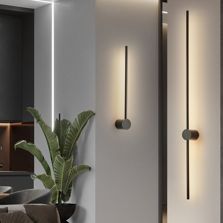 Deux appliques noires de longueurs différentes, l'une fixée par le bas, l'autre par le milieu, dans un salon moderne avec plante. 4