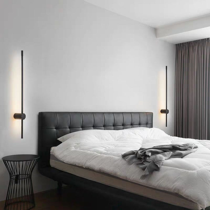 Deux appliques noires allumées de part et d'autre d'un lit à tête de lit capitonnée noire, dans une chambre épurée. 7