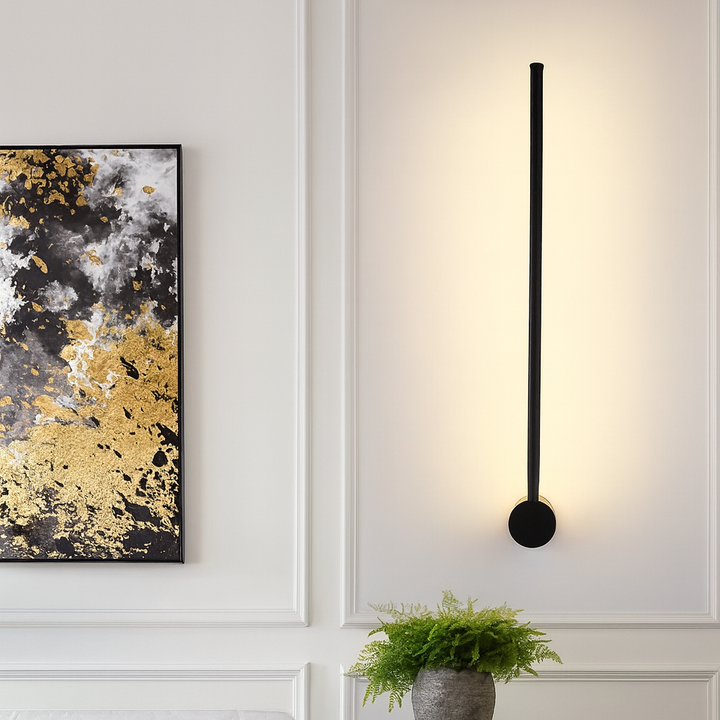 Applique noire à fixation ronde en bas, allumée sur un mur blanc à moulures, près d'un tableau doré et noir et d'une fougère. 8