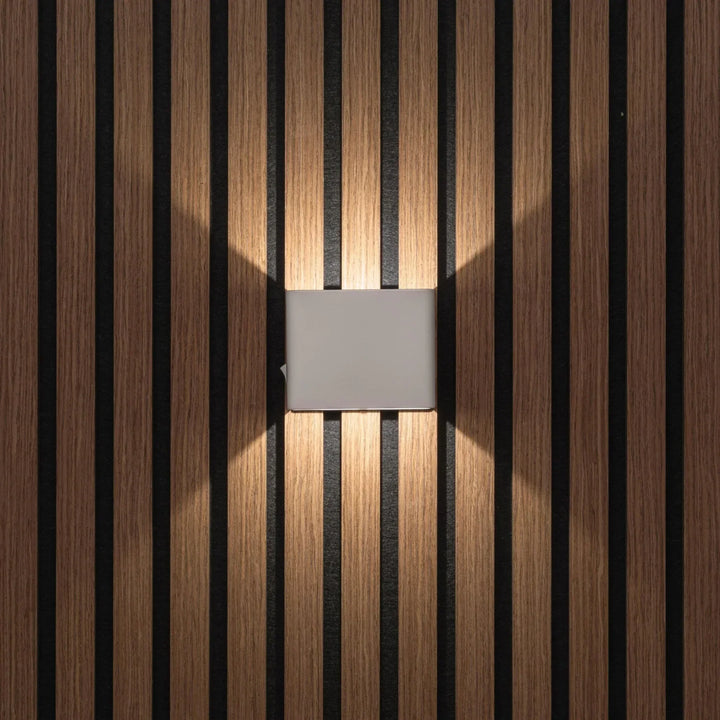 Applique cubique grise vue de face, éclairant vers le haut et le bas un mur de lattes en bois 6