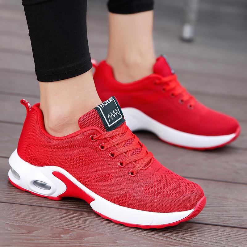 Gros plan sur une basket rouge en maille avec semelle blanche épaisse à bulle d'air, portée avec un legging noir. 5