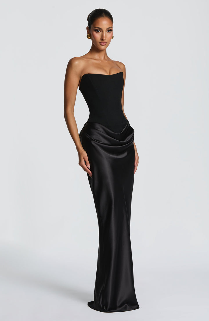 Robe noire portée par un mannequin, vue de trois quarts avec le drapé de la jupe en satin 24
