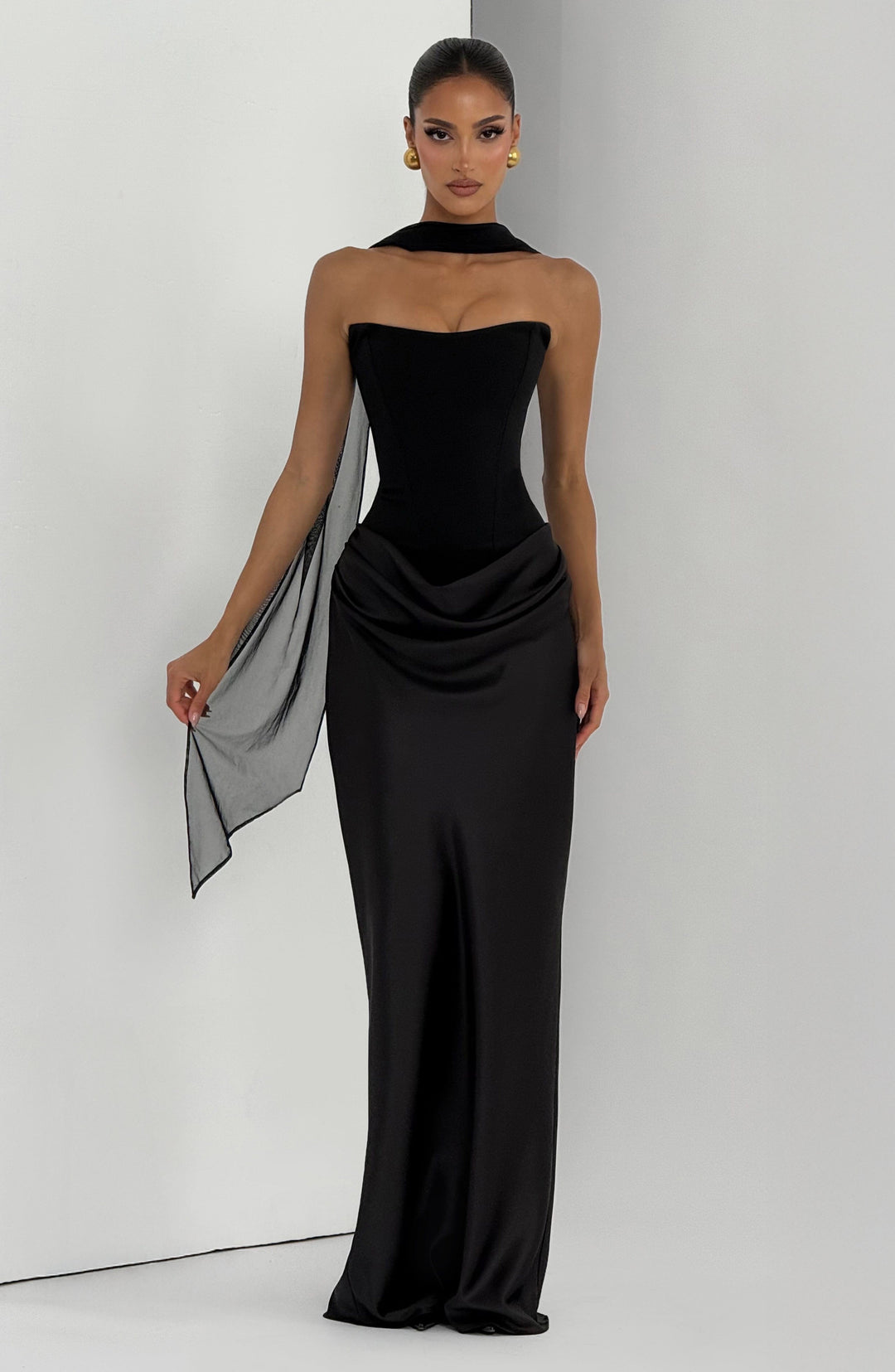 Robe noire de face avec voile léger sur une épaule, une main tenant le tissu 27