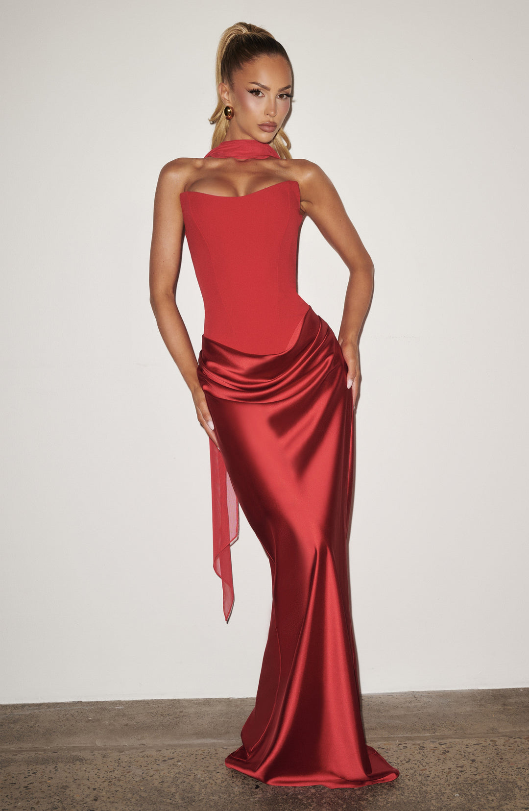 Robe rouge portée devant un mur blanc, foulard en voile noué au cou, mains sur les hanches 14