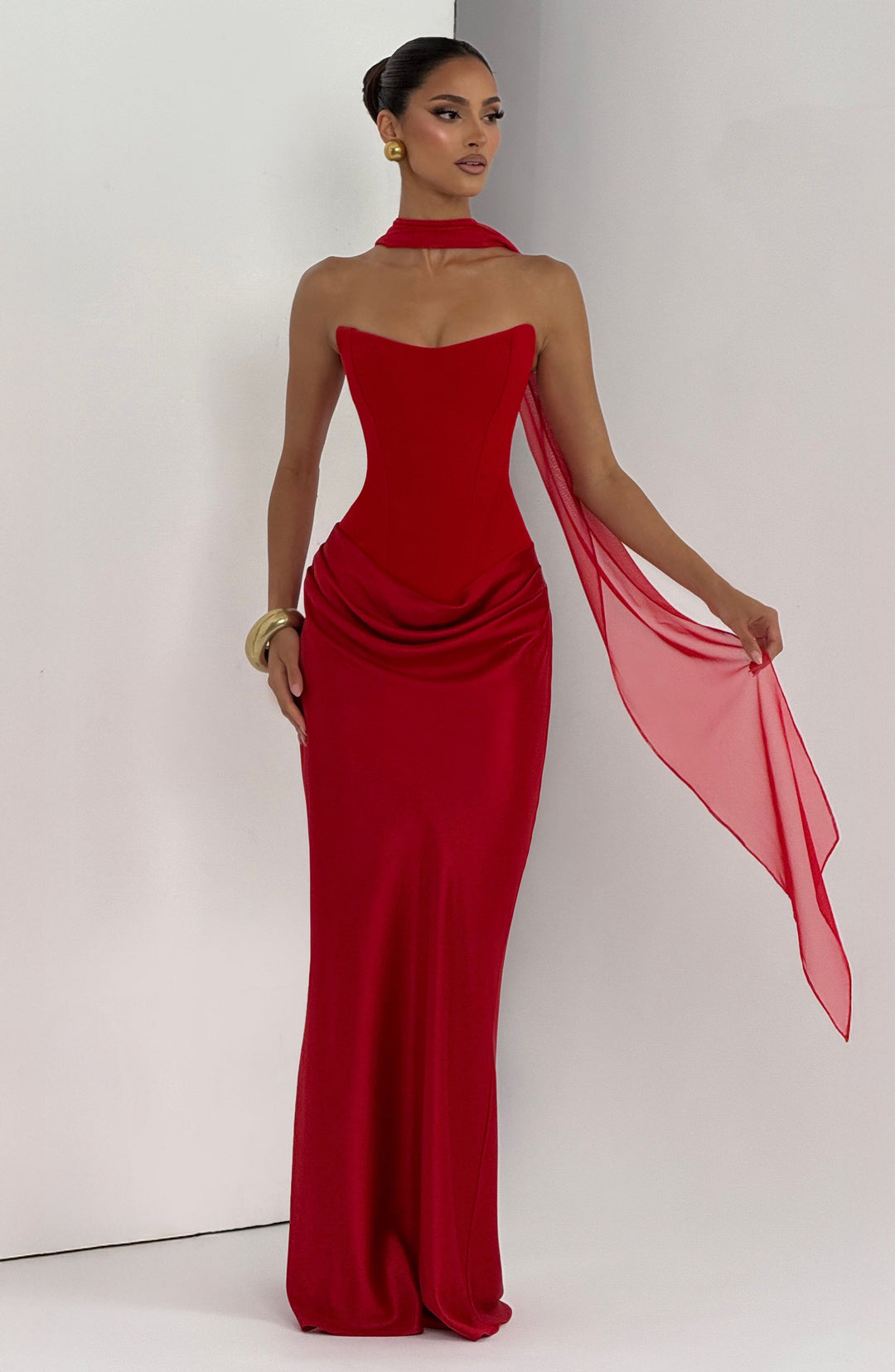 Robe rouge avec voile transparent tenu en l'air, bracelet doré, fond blanc et gris 19