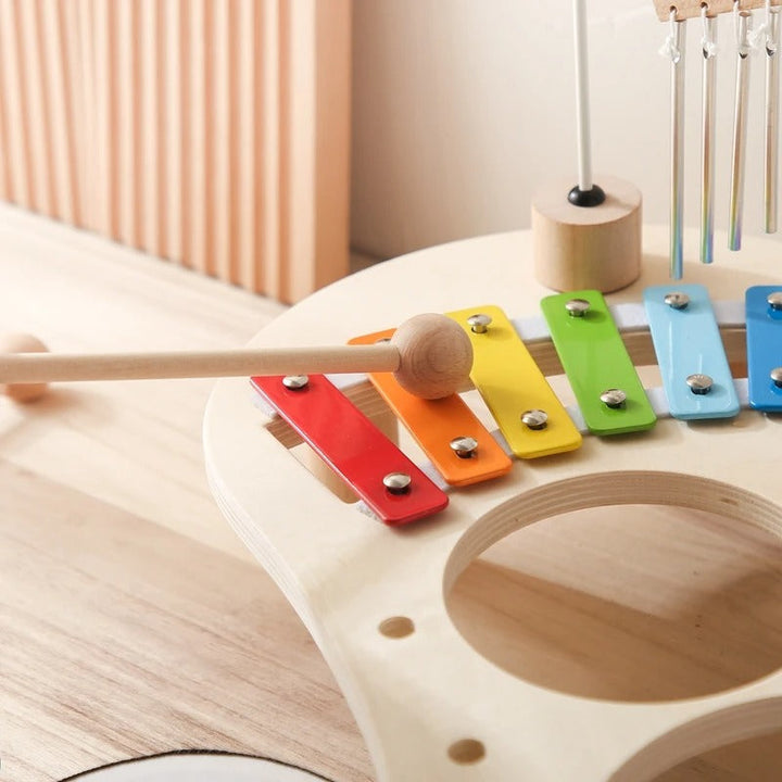 Gros plan sur les lames colorées du xylophone, une baguette posée dessus et l'ouverture des tambours 10