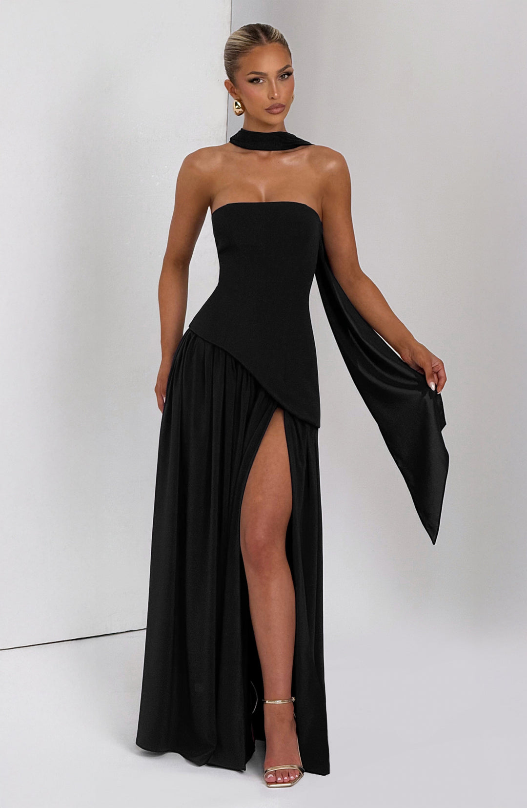 Robe noire de face, écharpe soulevée d'une main, fente haute sur la jupe fluide 10