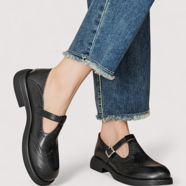 Babies noires en cuir à bride boucle portées avec un jean brut effiloché, l'une levée, vue de côté et de trois quarts. 4